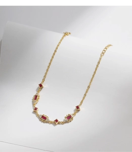 Detail view of gold bracelet with ruby rectangle stones and sparkling white zircons