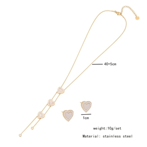 Detail view of gold stainless steel heart necklace and studs with white shell and crystals