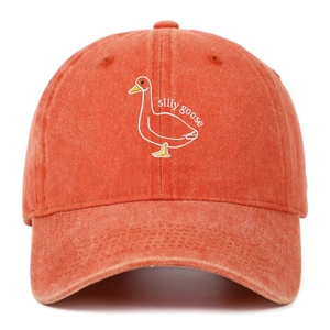 Detail of silly goose embroidery on washed orange cotton baseball cap with distressed brim