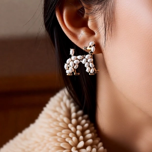 Detail of vintage poodle stud earring with pearls and gold finish on model's ear