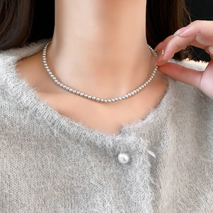Close-up of fine 3-4mm pearl necklace worn with a luxury grey knit cardigan for women