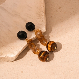 Retro resin chain link earrings with tiger eye stone and black beads on stone background