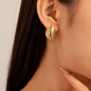Detailed close-up of golden mussel shell earrings with natural texture on female model