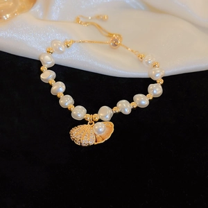 Detail showing baroque pearls and gold shell pendant with crystals on velvet background