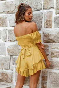 Detail der Rückenschleife und der gestuften Rüschen am gelben schulterfreien Minikleid
