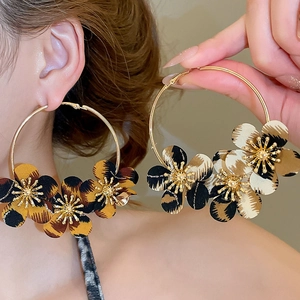 Close-up of golden hoop earrings with fabric leopard print flowers and golden stamens