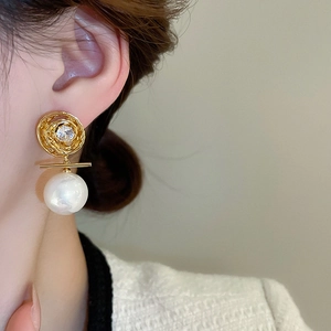 Détail de boucles d'oreilles perles plaquées or avec zircon étincelant sur un modèle