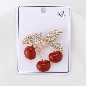 Macro detail of red cherry brooch with gold stem and sparkling white rhinestones