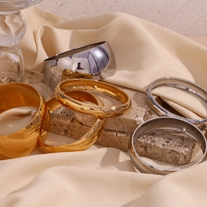 Close-up of polished gold and silver minimalist bangles on elegant silk fabric