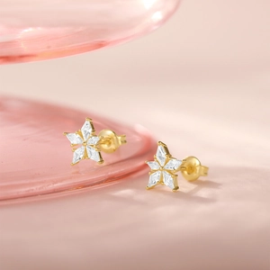 Macro shot of gold star studs with inlaid opal and diamonds on a soft pink background