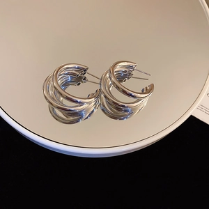 Macro view of triple-layered silver hoop earrings with clear reflection on mirror surface
