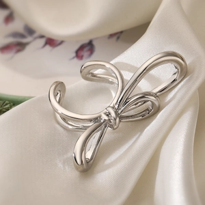 Elegant 18K gold plated bow-shaped open ring on white silk fabric, minimalist style