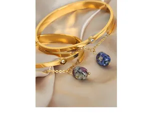 Detailed shot of gold plated titanium bracelet with blue natural stone charms on silk