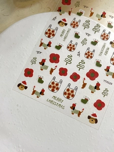 Macro detail of 3D embossed Christmas nail stickers with red flowers and puppy motifs