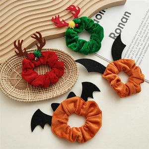 Holiday velvet scrunchies with reindeer antlers and bat wings decorations on white desk