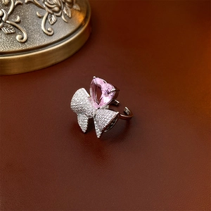 Détail de la bague avec pierre de cœur rose et nœud argenté serti de zircons