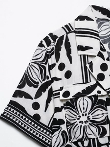Close-up of tropical leaf print and pocket detail on black and white cotton romper