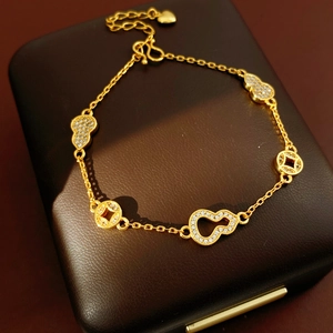Detailed close-up of 24k gold-plated gourd and coin bracelet charms with pavé zircon