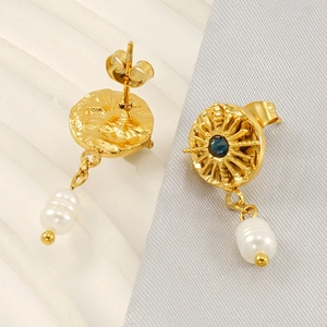 Golden sunburst earrings with blue crystal and white pearl charms on satin background