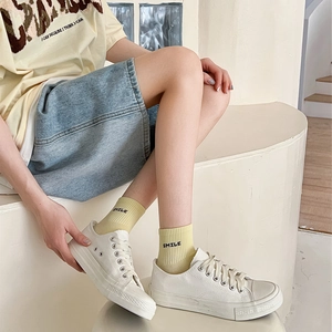 Detail of SMILE embroidered cotton socks paired with cream white canvas sneakers