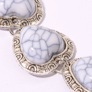Macro detail of vintage heart bracelet with marble turquoise and retro scroll engravings