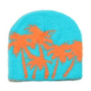 Close-up of sky blue knit beanie featuring an orange coconut tree jacquard pattern