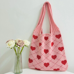 Close-up of pink knitted tote bag with red heart pattern and diamond grid texture