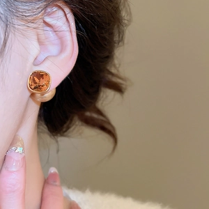 Close-up of square amber crystal earring with 18K gold plating on model's ear