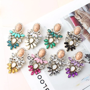 Detailed flat lay of boho vintage crystal drop earrings in multiple colors on a magazine