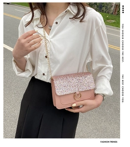 Pink sequin crossbody bag with gold chain strap shown on a model during a street photoshoot