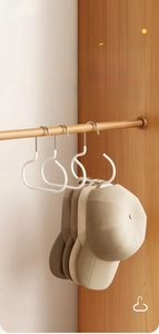 Detail view of round white ABS hat hooks hanging on a closet rod for scarf storage
