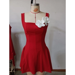 Détail de robe courte rouge sans manches avec fleurs 3D en tissu et perles centrées