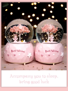 Macro detail of a pink cherry blossom snow globe featuring an angel and Best Wishes slogan
