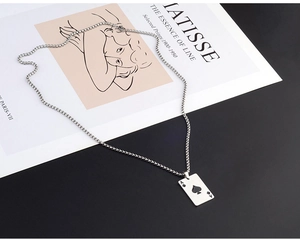 Detail of silver Ace of Spades poker pendant with box chain on artistic background