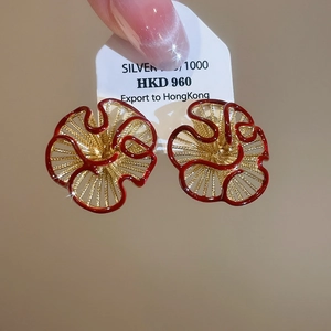 Macro shot of gold-plated red enamel earrings with radial texture on a silver needle base