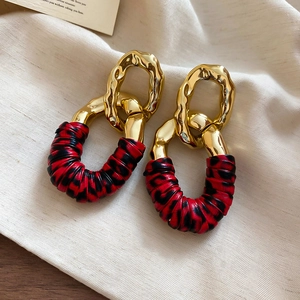 Close-up of golden irregular metal rings with red and black leopard print leather wrap