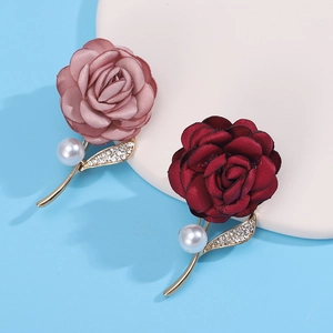 Close-up of pink and deep red fabric rose brooches with pearls and rhinestones