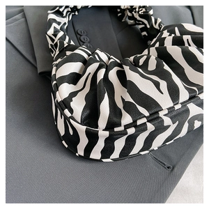 Detail of zebra pattern ruched cloud bag showing textured leather on grey suit blazer