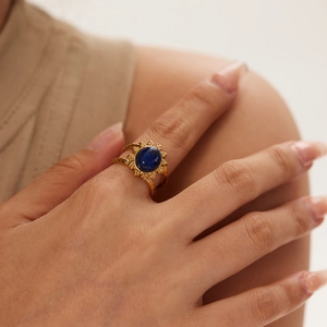 Detail of vintage gold ring with oval blue gemstone and sunburst engraving texture