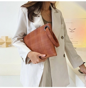 Dettaglio della pochette a quadri marrone-arancio con grande anello metallico e cinturino