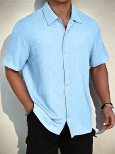 Detail of light blue short sleeve shirt showing textured fabric and precise stitching