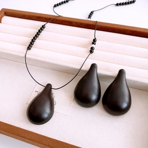 Flat lay of teardrop resin pendant necklace with wooden texture beads on a jewelry tray
