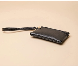 Macro shot of black litchi texture coin purse with golden metal zipper and wrist strap