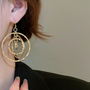 Close-up of gold layered circular earrings with hammered texture on female model