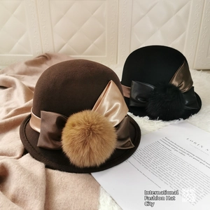 Detail of wool cloche hats with decorative satin bows and large fluffy pom-poms