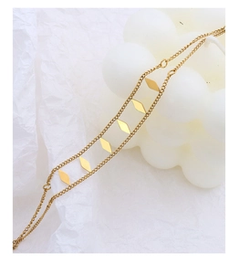 Macro detail of gold-plated double-layer geometric chain bracelet on a white background