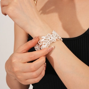 Details einer silbernen Manschetten-Armspange mit hohlem Blumenmuster am Handgelenk