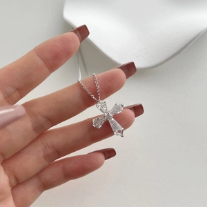 Macro shot of silver cross pendant featuring four large faceted zircons on a delicate chain
