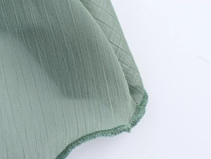 Detaillierte Makroaufnahme von grünem Chiffonstoff mit feiner Overlock-Nahtführung