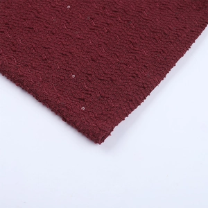 Vue macro détaillée du tissu en maille bordeaux avec vagues texturées et paillettes
